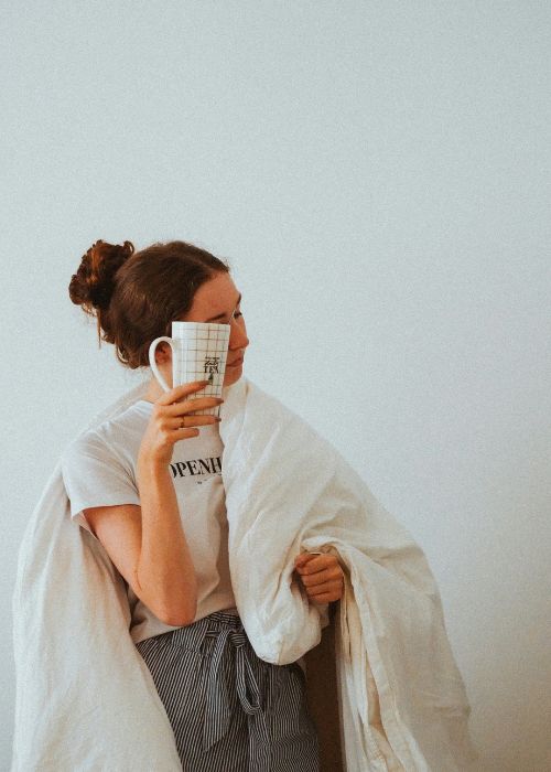 woman wrapped in a cozy blanket holding a warm mug on a tough day